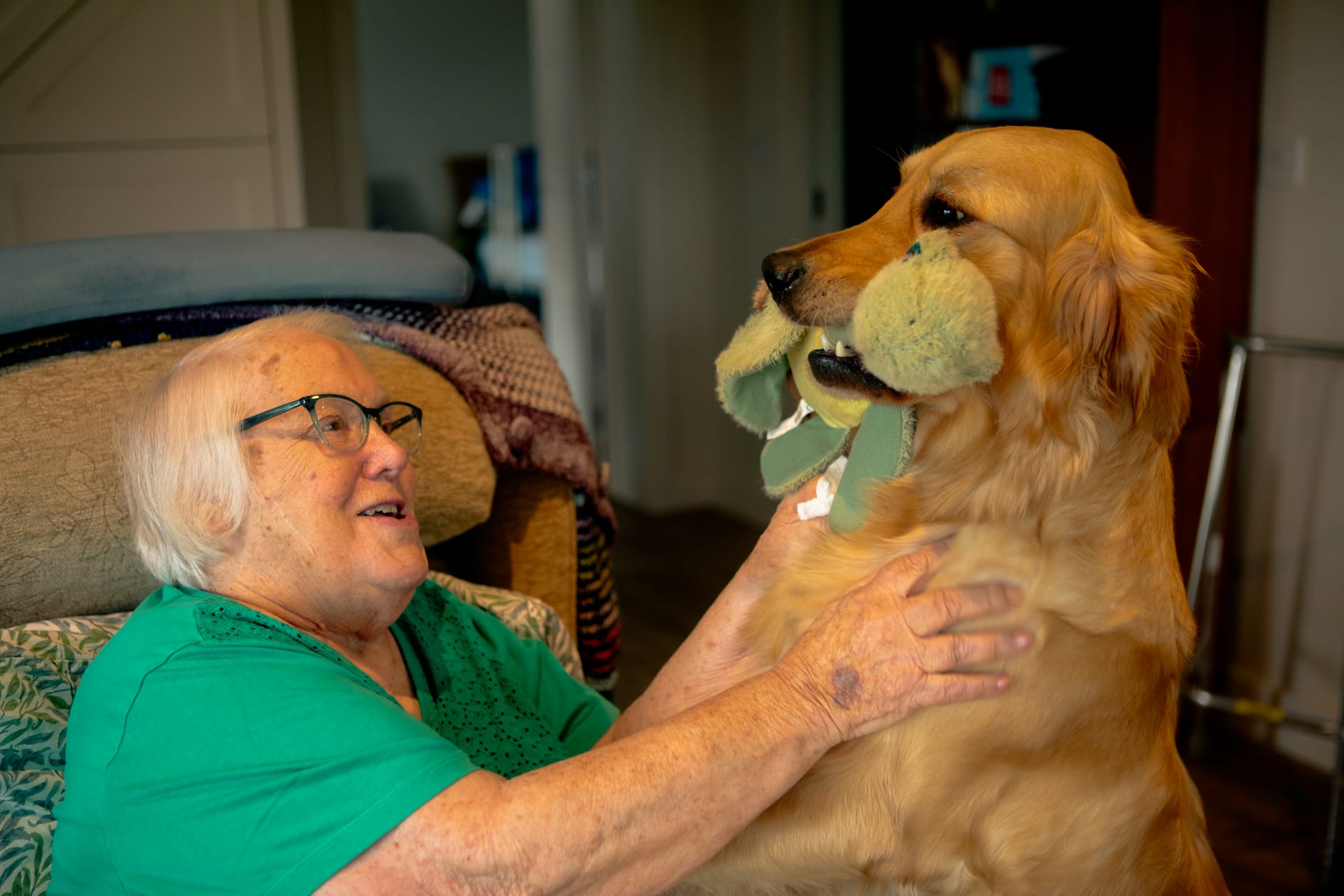 A Nutshell resident smiling warmly with her golden retriever companion at home